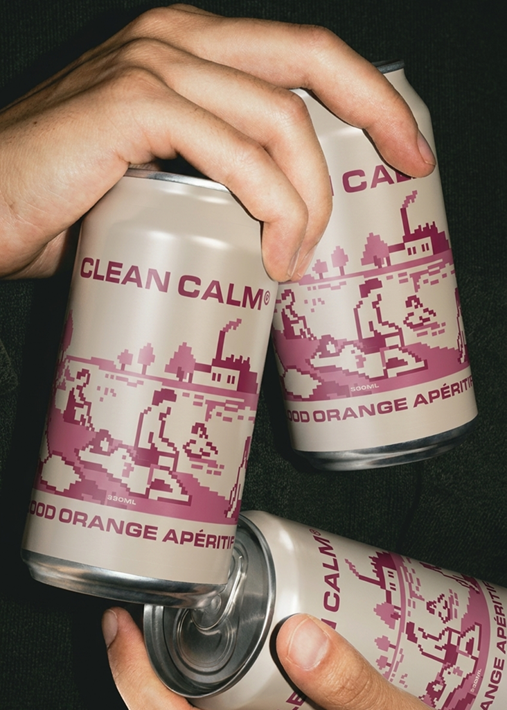 Hands holding three CLEAN CALM Blood Orange Apéritif cans against dark fabric